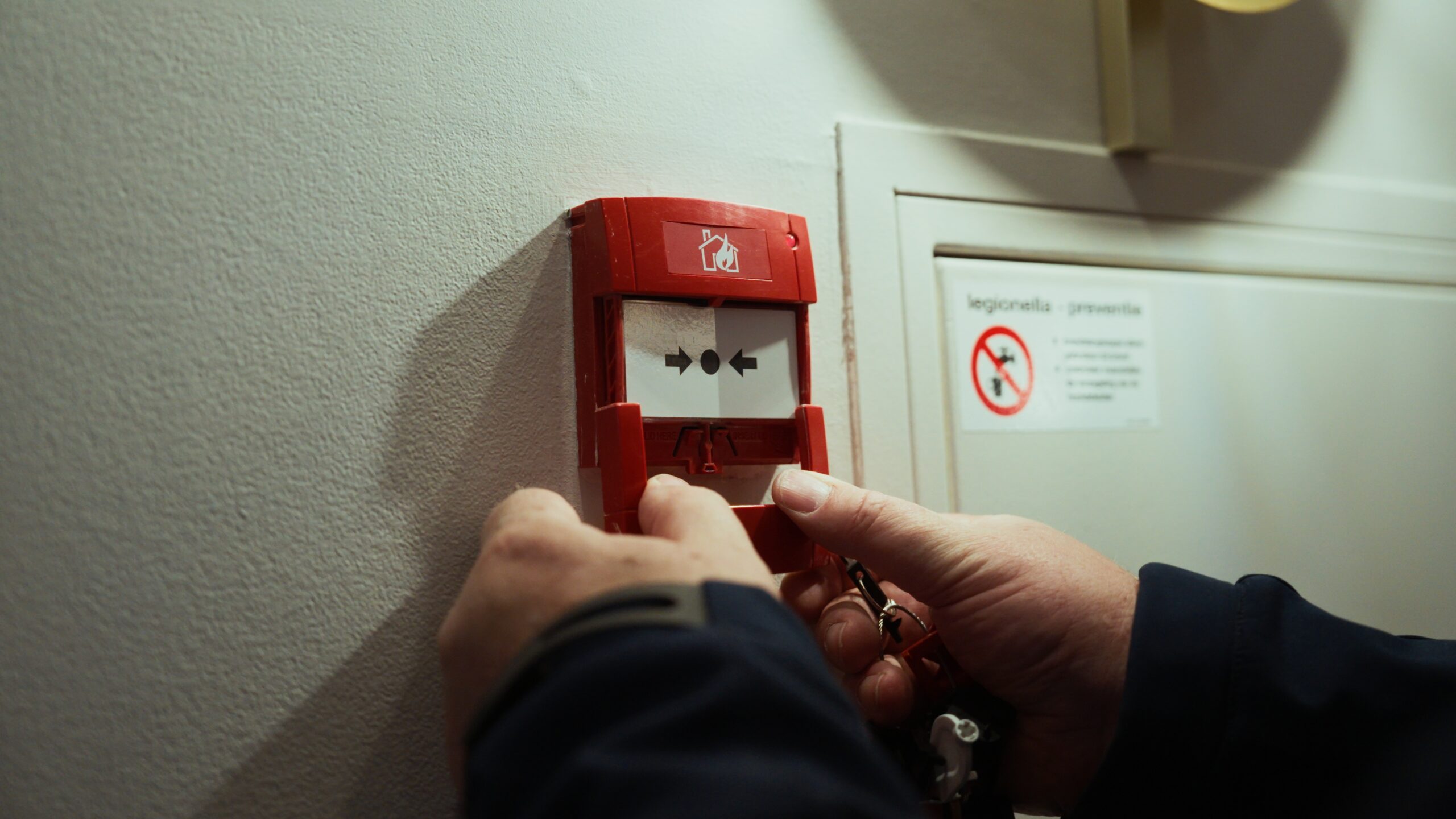 Handmelder die getest wordt door een Beheerder Brandmeldinstallaties van Hefas Brandbeveiliging.